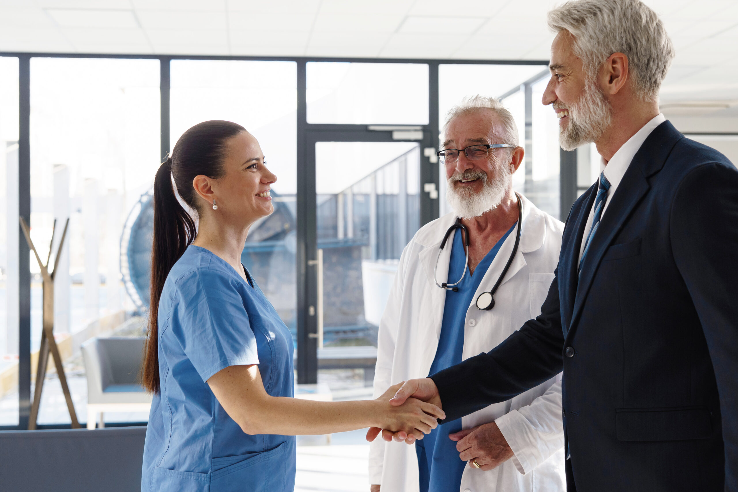 Medical sales representative presenting new medication to doctors, standing hospital hallway. Hospital setting.